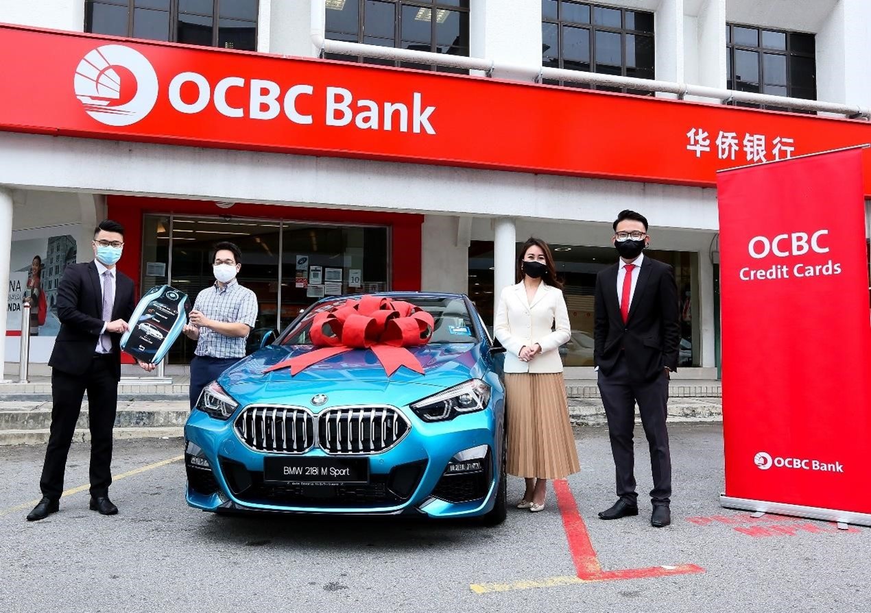 Sky Pang (Regional Manager & Senior Manager of OCBC Kajang Branch) handing over the “keys” to Dato Kenneth Chen, witnessed by OCBC staff members Shirley Ong and Yoong Tzi Vin in front of the OCBC Kajang branch 